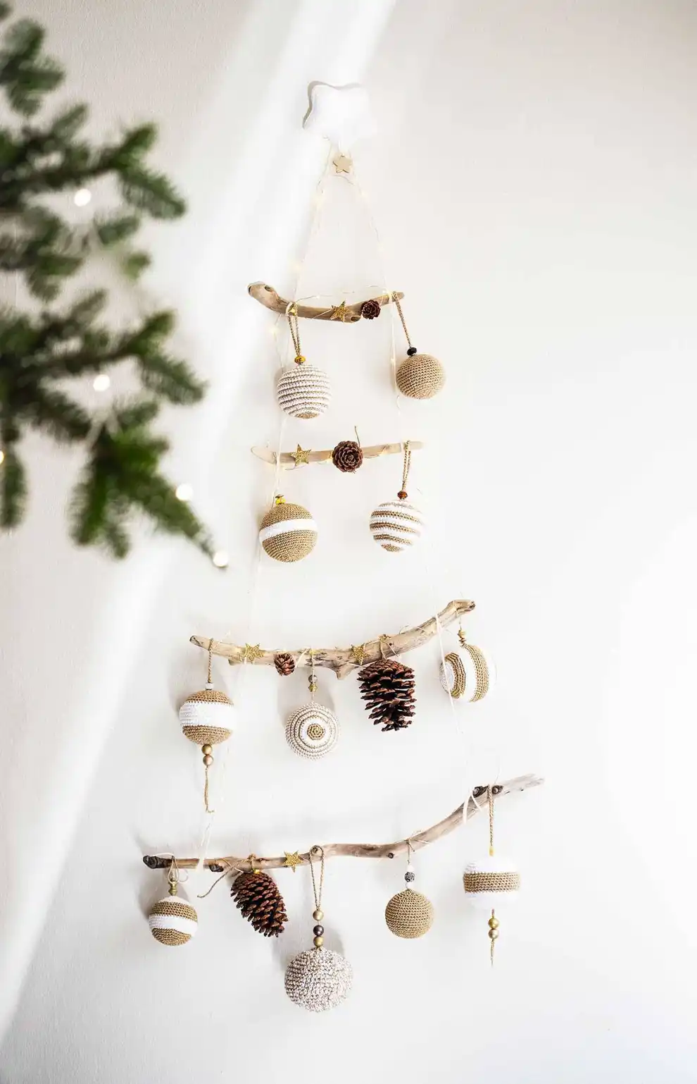 Árbol de Navidad hecho con ramitas y colgado en la pared