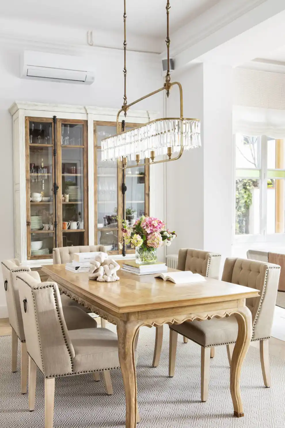 Comedor con mesa de madera con patas contorneadas y sillas tapizadas con tachuelas