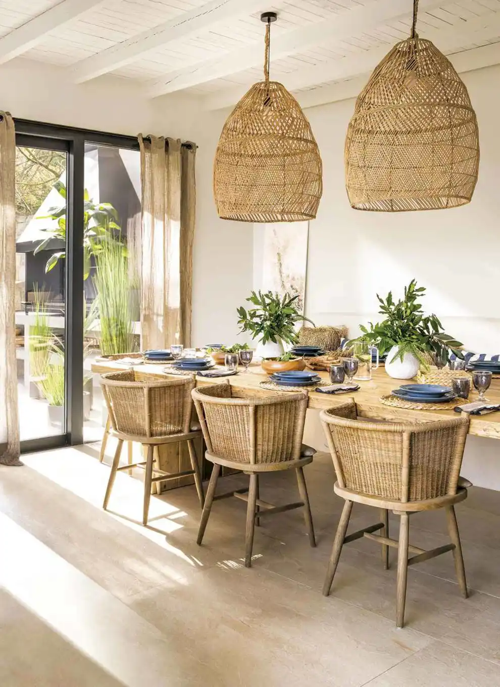 Comedor decorado con mesa de madera y sillas y lámpara de techo en ratán