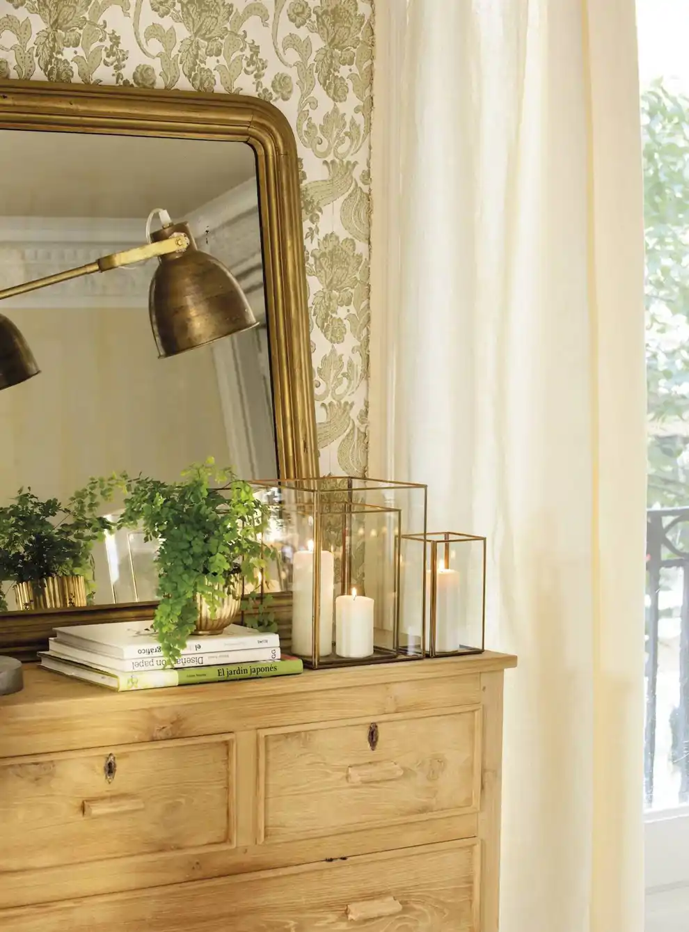 Cómoda de madera con velas, espejo y lámpara dorada