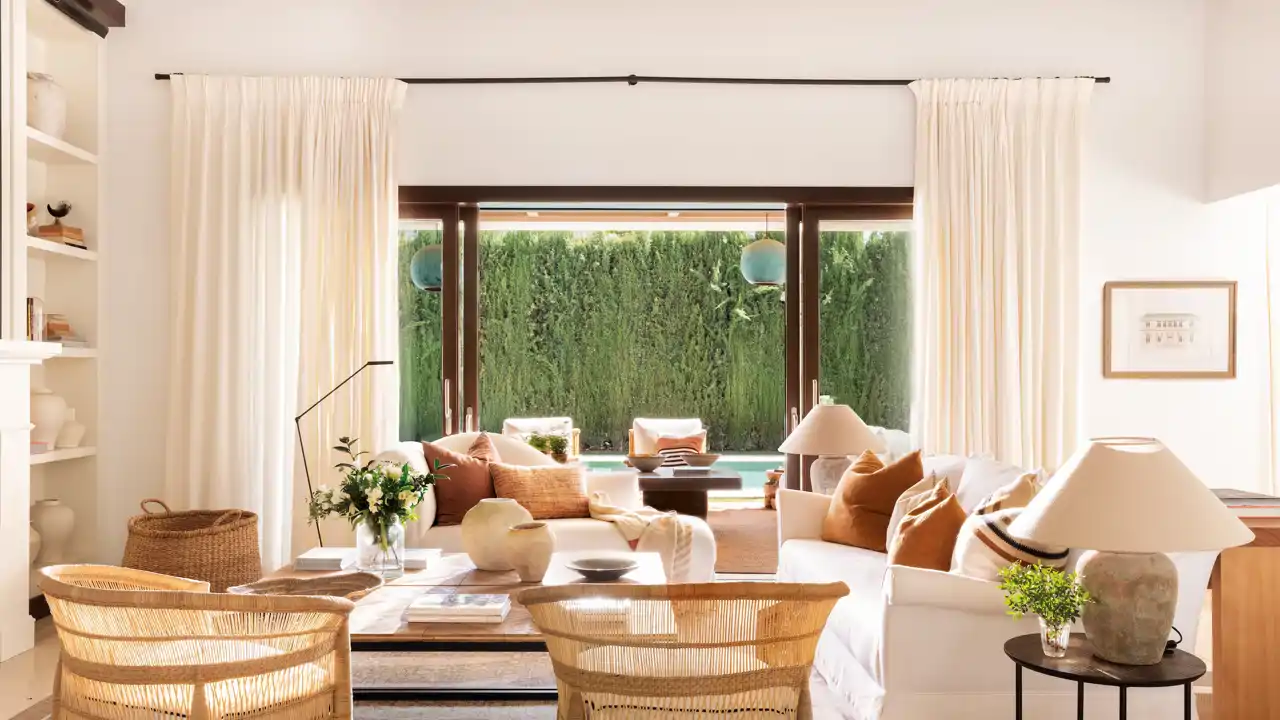 00573415 Salón con butacas de mimbre y gran ventanal con cortinas beige claro