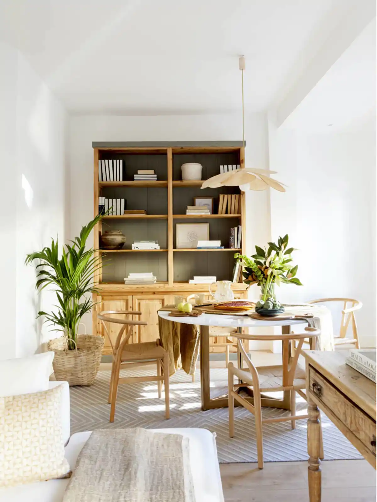 Comedor de estilo moderno con librería y sillas en madera y mesa redonda con superficie superior de mármol